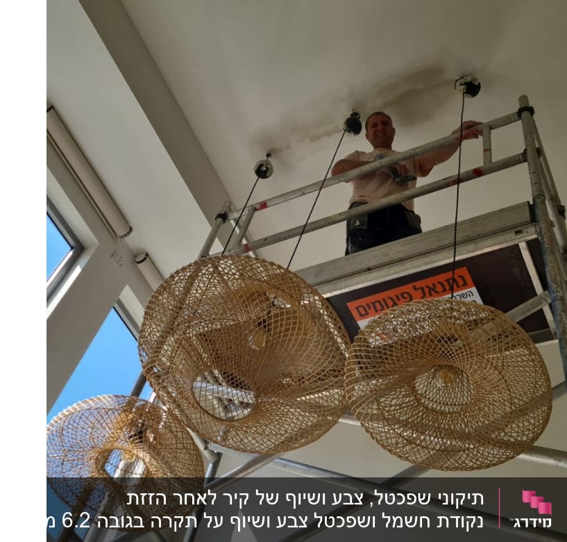 אדם על פיגום צובע תקרה בלבן